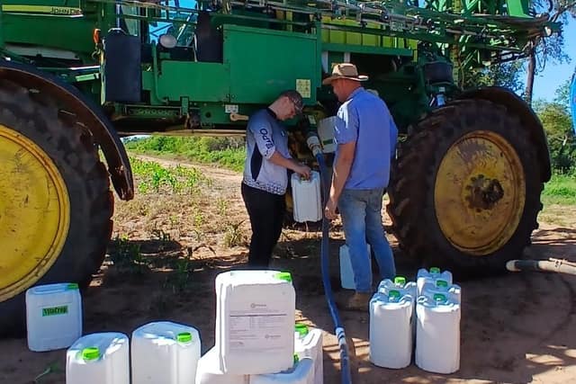 Bidones junto a una pulverizadora autopropulsada durante la carga del caldo