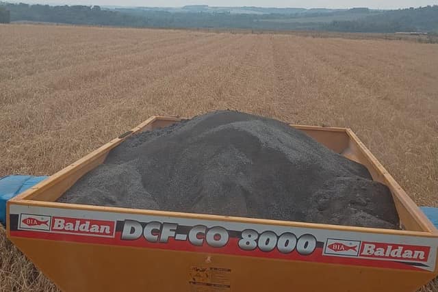 Tolva de una esparcidora cargada con CARBOterra en polvo, lista para aplicar al voleo
